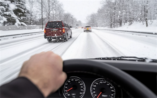 First-person view of a driver operating a vehicle on a snow-covered road, representing the real-world use of driver assistance systems in harsh winter conditions.